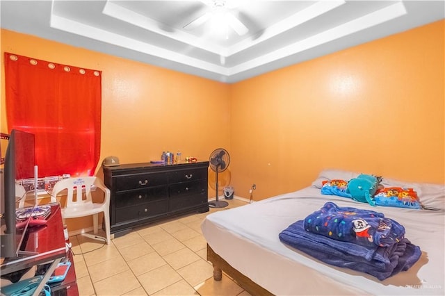 bedroom with ceiling fan, a tray ceiling, and light tile patterned floors