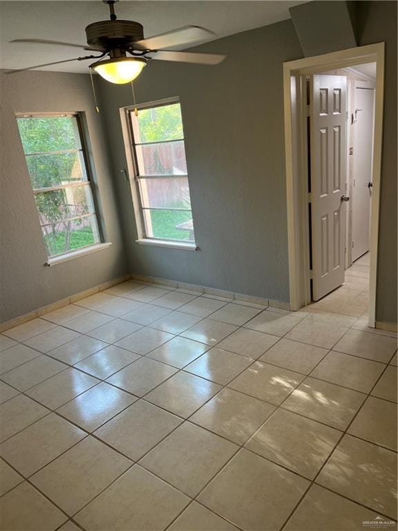 tiled spare room with ceiling fan