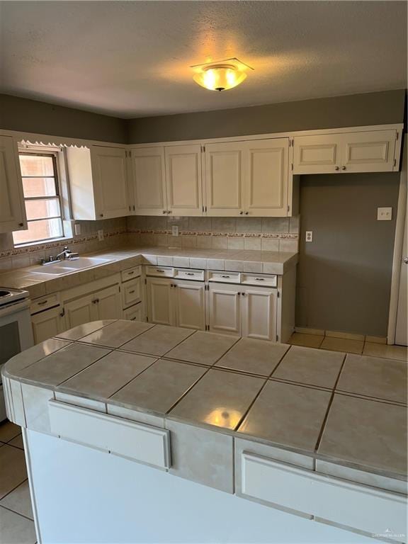 kitchen with decorative backsplash, tile counters, light tile patterned floors, and sink