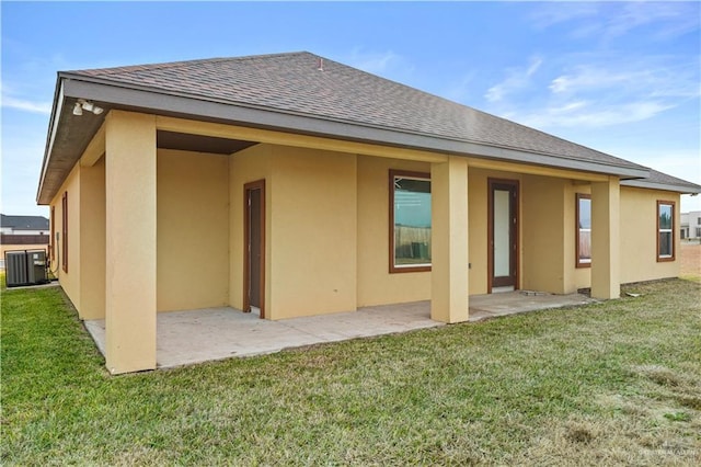 rear view of house featuring a lawn, central AC, and a patio area