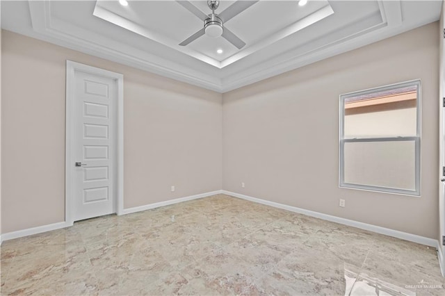 empty room with ceiling fan and a raised ceiling