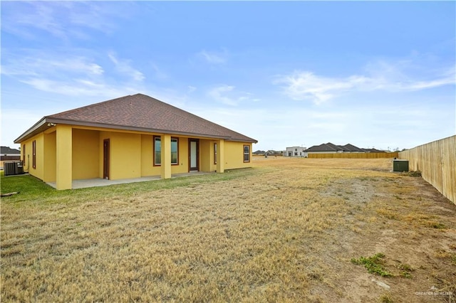 rear view of property with central AC, a patio, and a lawn