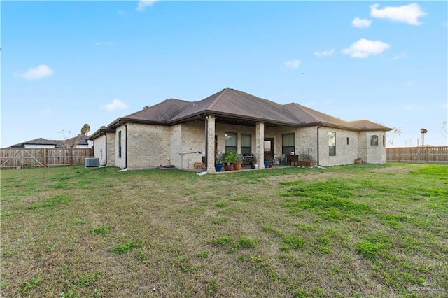 back of property featuring central AC unit and a lawn