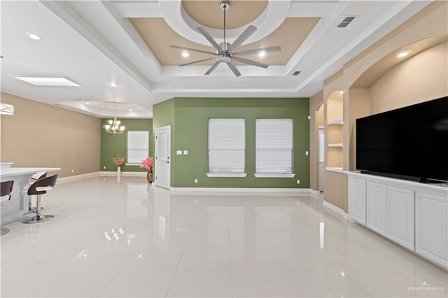 unfurnished living room with light tile patterned flooring, ceiling fan with notable chandelier, and a tray ceiling