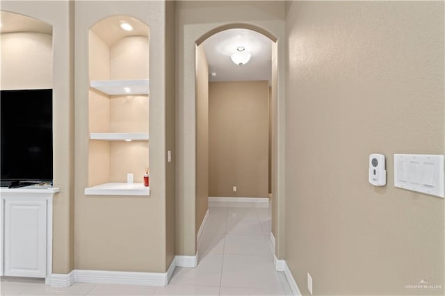 corridor with built in shelves and light tile patterned flooring