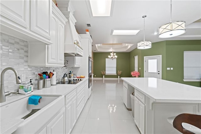 kitchen featuring sink, hanging light fixtures, white cabinets, black electric cooktop, and a raised ceiling