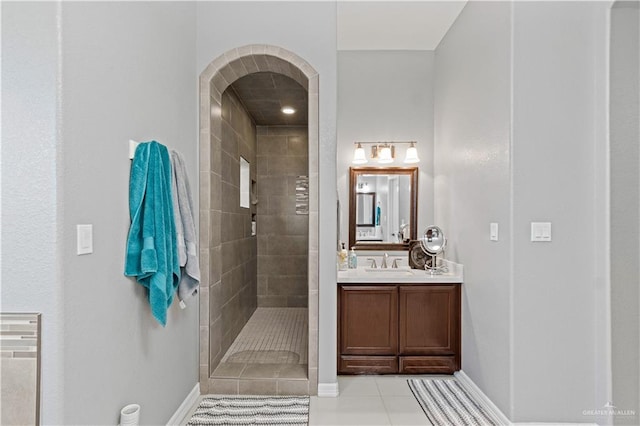 bathroom with tile patterned flooring, vanity, and a tile shower