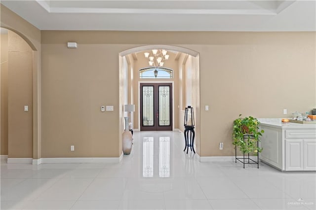 entrance foyer featuring light tile patterned floors, a notable chandelier, and french doors