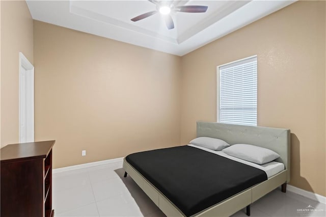 bedroom featuring light tile patterned floors, ceiling fan, and a tray ceiling