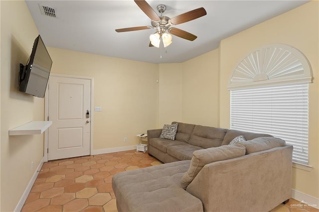 living area with light tile patterned floors, baseboards, visible vents, and a ceiling fan