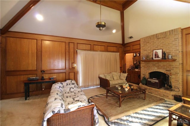 carpeted living room with wooden walls, beam ceiling, high vaulted ceiling, and a brick fireplace