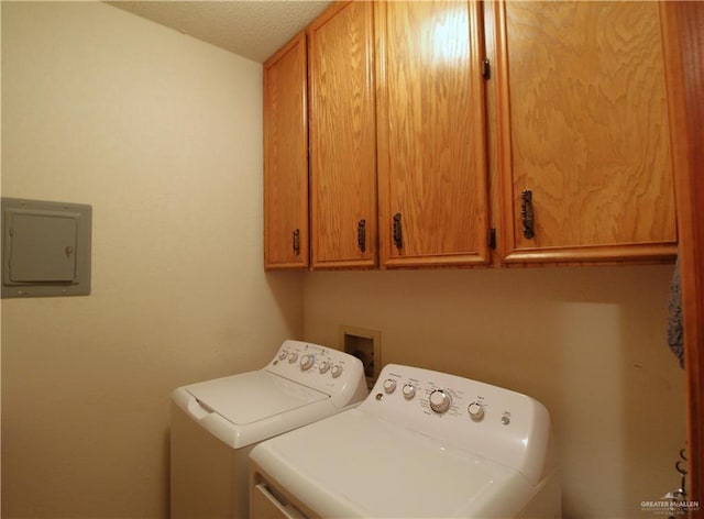 washroom featuring electric panel, cabinets, washer and dryer, and a textured ceiling