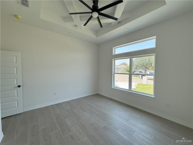 spare room with visible vents, baseboards, a raised ceiling, and wood finished floors