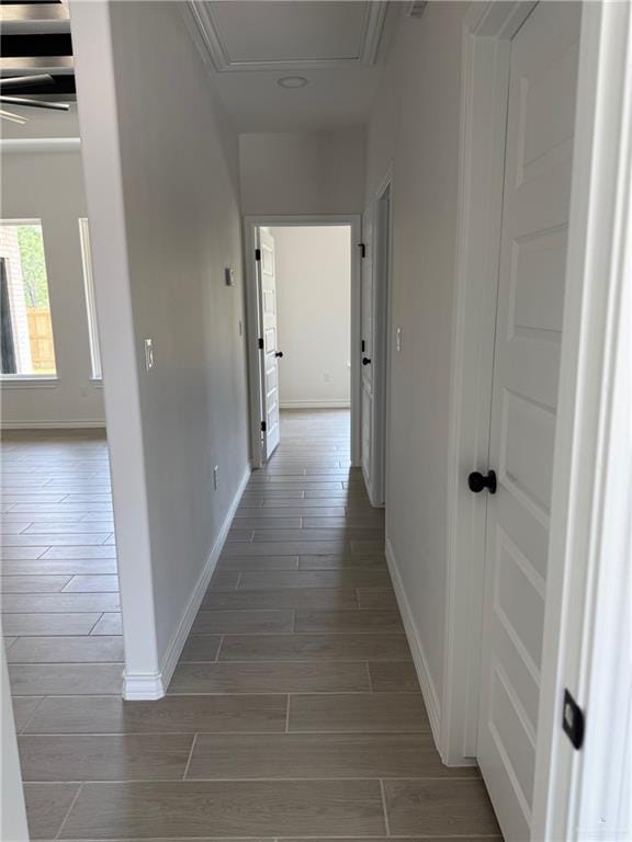 corridor featuring baseboards, wood tiled floor, and attic access