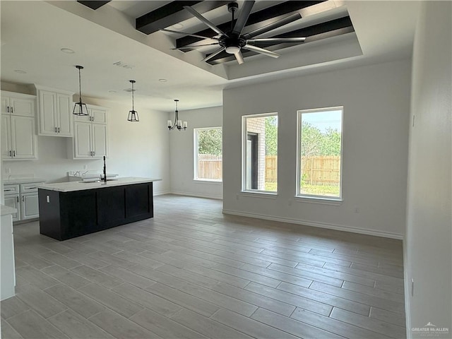 interior space featuring a sink, beam ceiling, ceiling fan with notable chandelier, baseboards, and visible vents