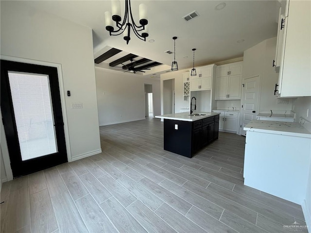 kitchen featuring visible vents, open floor plan, white cabinetry, a sink, and hanging light fixtures