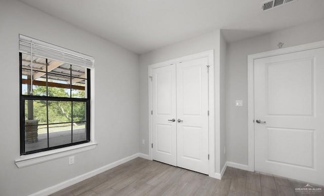 unfurnished bedroom with light wood-type flooring and a closet