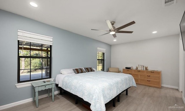 bedroom featuring multiple windows, light hardwood / wood-style floors, and ceiling fan