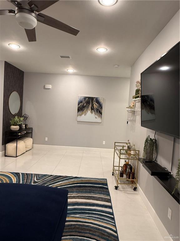 tiled living room featuring a ceiling fan, visible vents, and baseboards