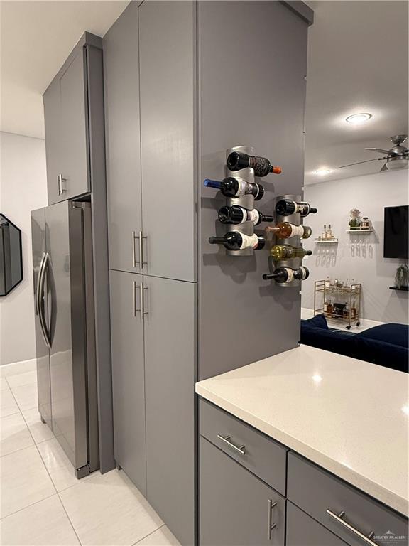 kitchen featuring light tile patterned floors, light countertops, gray cabinetry, ceiling fan, and stainless steel fridge