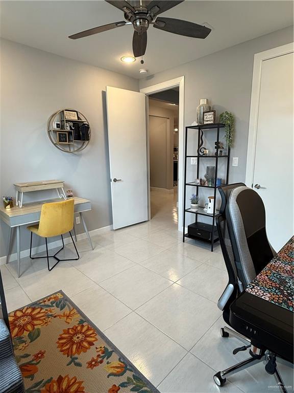 office space with light tile patterned floors, ceiling fan, and baseboards