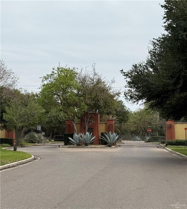 view of street with a gate, curbs, and a gated entry