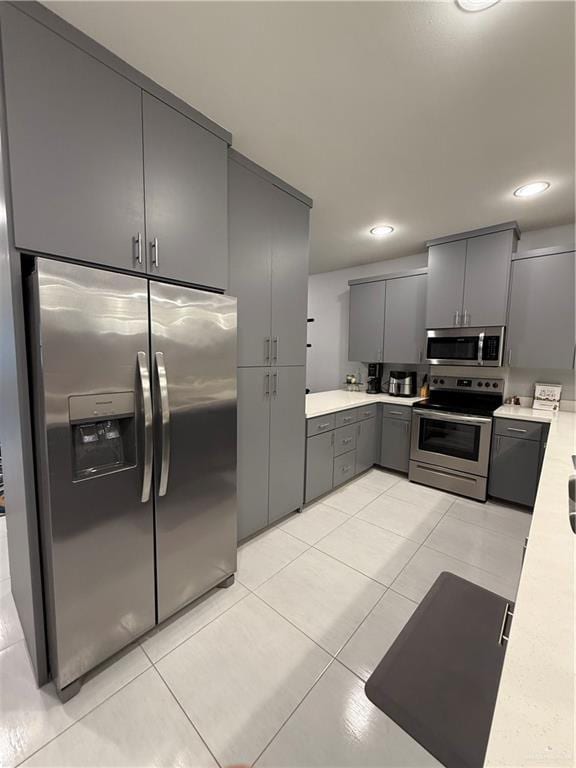 kitchen with light tile patterned floors, recessed lighting, gray cabinetry, light countertops, and appliances with stainless steel finishes