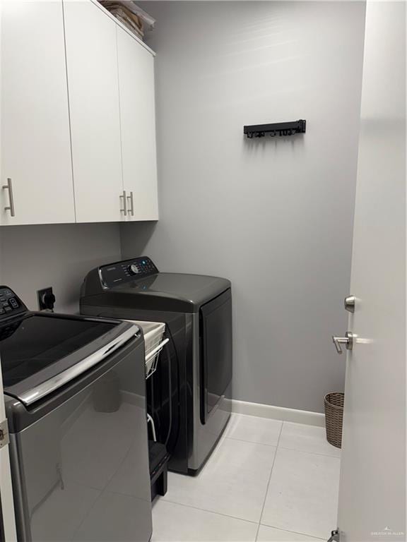 laundry area featuring light tile patterned floors, independent washer and dryer, cabinet space, and baseboards