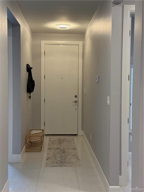 doorway featuring baseboards and light tile patterned flooring