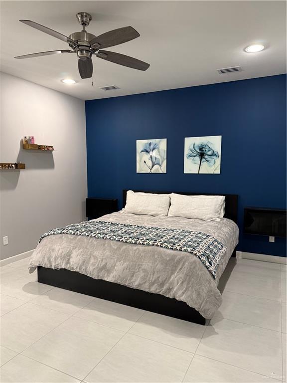 bedroom featuring ceiling fan, light tile patterned floors, visible vents, and baseboards