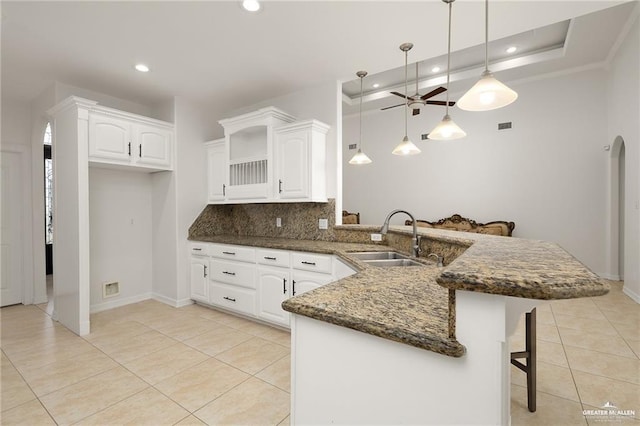 3213 Academy Ave, Edinburg, TX 78541 - kitchen featuring a peninsula, a kitchen bar, decorative backsplash, ceiling fan, and light tile patterned flooring
