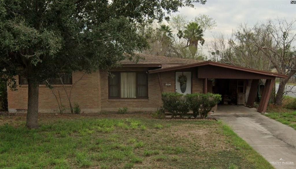 521 W Sycamore Ave, Mcallen, TX 78501 - view of front facade with driveway, brick siding, an attached carport, and a front yard