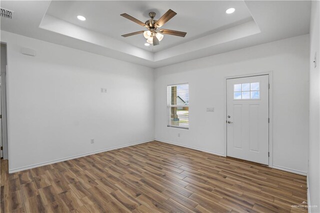 foyer entrance with a tray ceiling, dark hardwood / wood-style floors, and ceiling fan