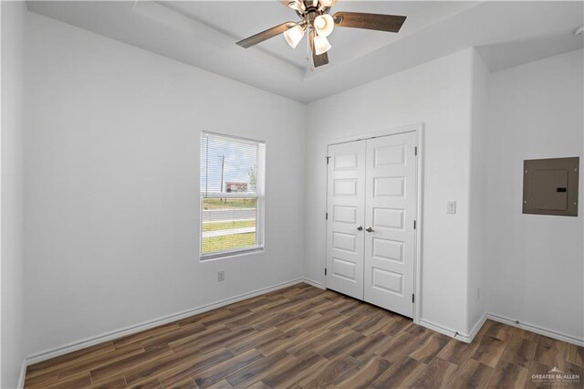 unfurnished bedroom with ceiling fan, dark hardwood / wood-style flooring, electric panel, and a closet