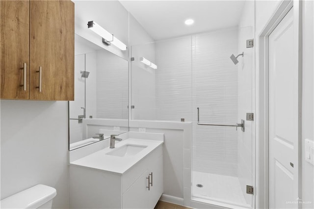 bathroom with walk in shower, vanity, and toilet