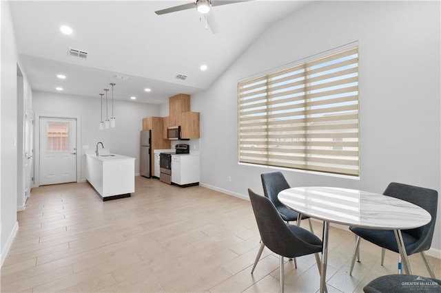 dining area with ceiling fan, lofted ceiling, light hardwood / wood-style floors, and sink