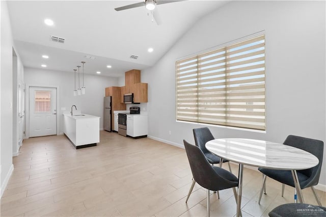 dining area with vaulted ceiling, sink, ceiling fan, and light hardwood / wood-style floors