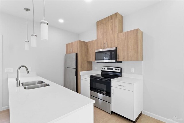 kitchen featuring white cabinetry, stainless steel appliances, decorative light fixtures, and sink