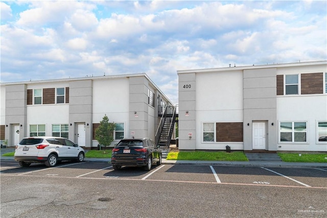 view of building exterior with uncovered parking and stairway
