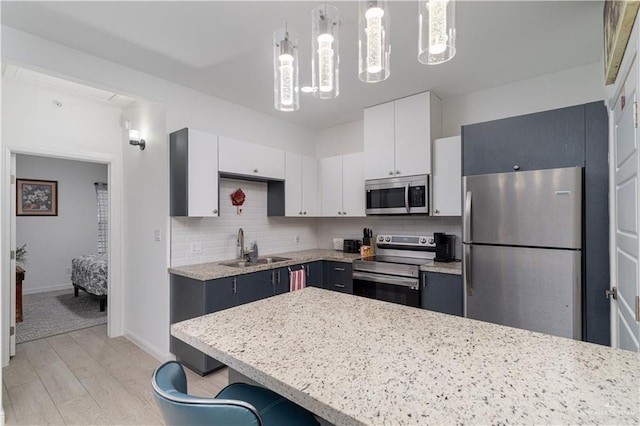 901 E Yuma Ave Unit 504, Mcallen, TX 78503 - kitchen featuring stainless steel appliances, a sink, light wood finished floors, decorative backsplash, and white cabinetry