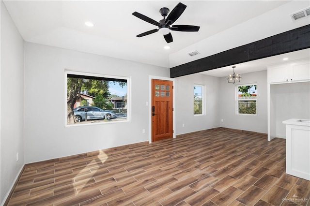 unfurnished living room featuring ceiling fan with notable chandelier