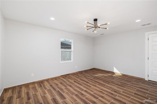 spare room with a chandelier and dark hardwood / wood-style floors