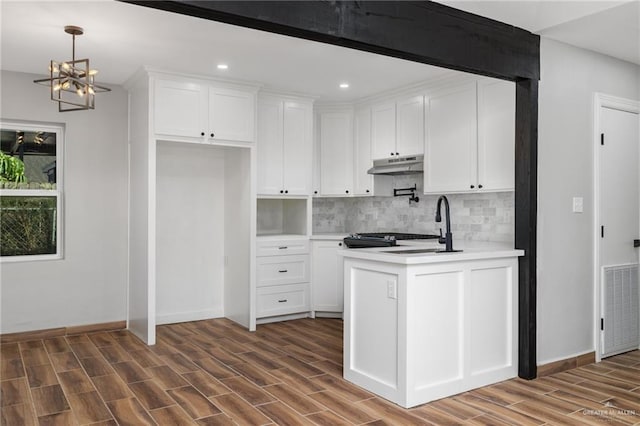 kitchen with decorative backsplash, a chandelier, white cabinetry, and sink