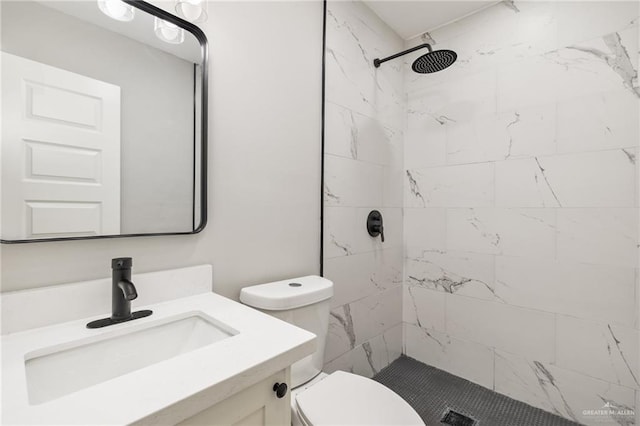 bathroom with vanity, toilet, and tiled shower