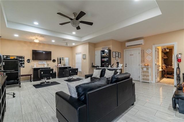 living room featuring a wall mounted AC, ceiling fan, and a tray ceiling