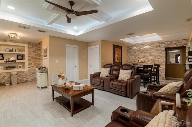 living room with a skylight, coffered ceiling, ceiling fan, beam ceiling, and built in shelves