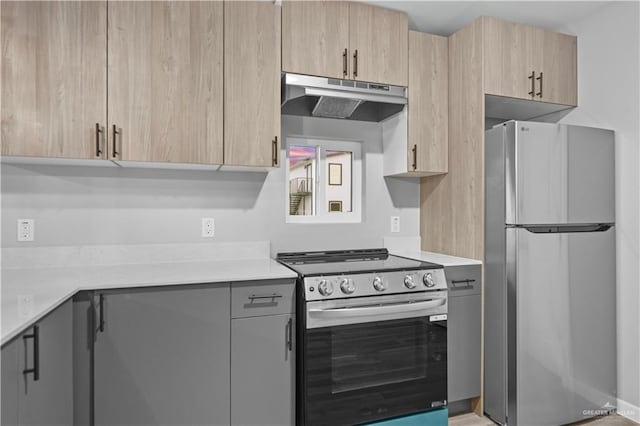 kitchen with under cabinet range hood, appliances with stainless steel finishes, light countertops, and light brown cabinetry