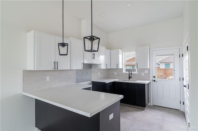 kitchen with sink, backsplash, kitchen peninsula, decorative light fixtures, and white cabinets