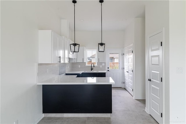 kitchen featuring kitchen peninsula, tasteful backsplash, sink, decorative light fixtures, and white cabinets