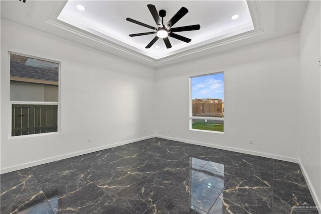 spare room with a raised ceiling and ceiling fan